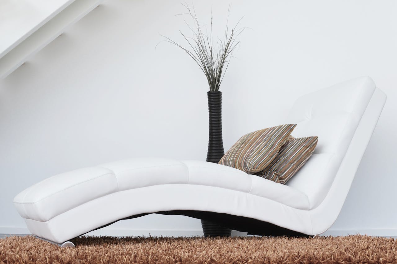 about-02 Elegant white lounge chair with cushions on plush carpet, perfect for relaxation.