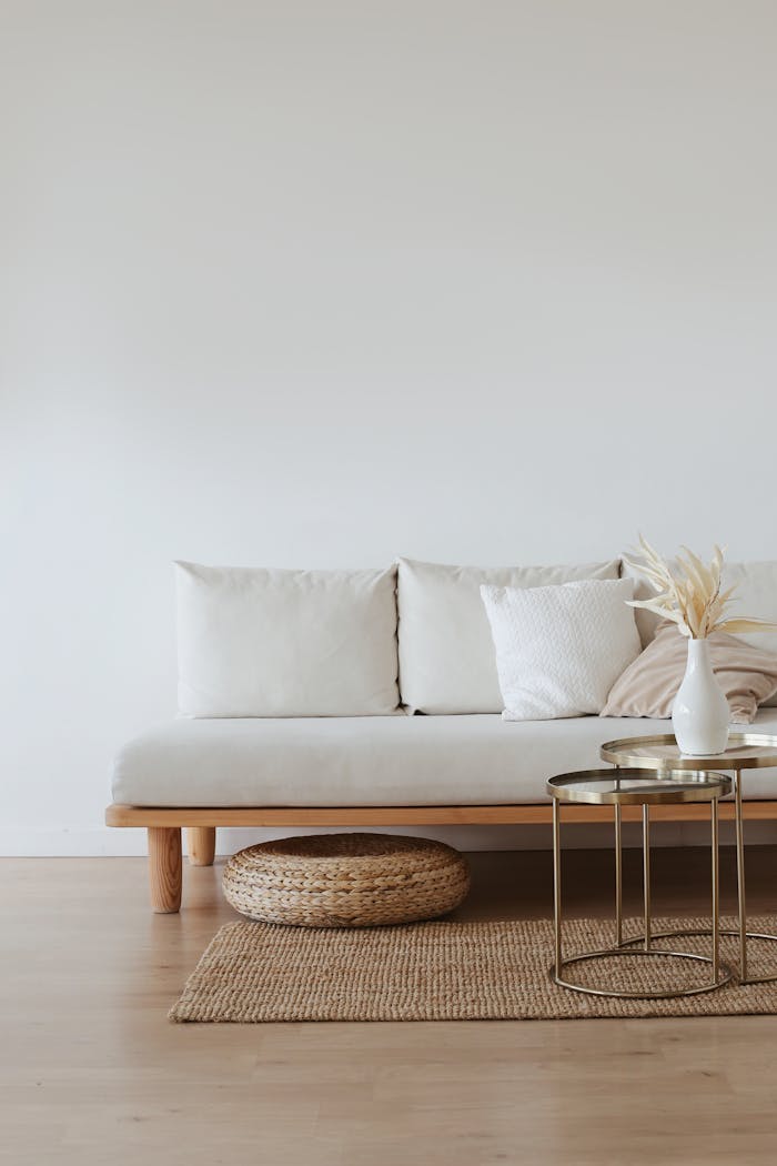 awards-img A chic minimalist living room featuring a white sofa with cushions, dried flowers in a vase, and a wooden floor.